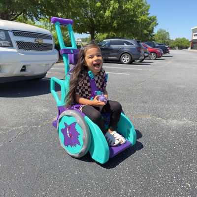 Girl uses turquoise and purple Toddler Mobility Trainer